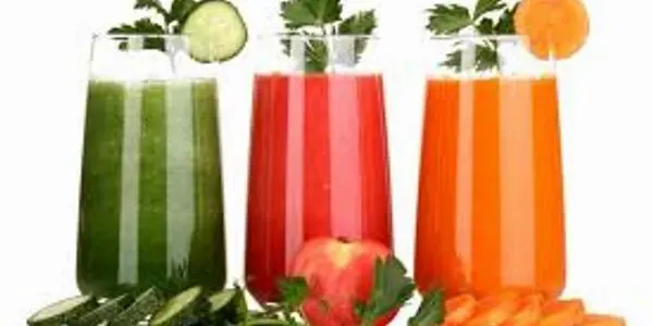 Three glasses of juice with a cucumber and tomato