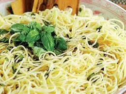 A bowl of noodles with basil on top.