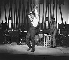 A man in a tie and suit on stage.
