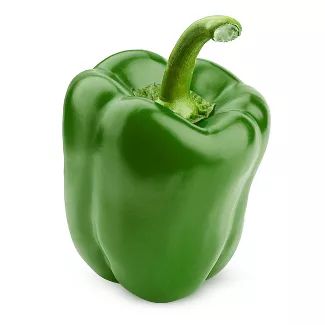 A green bell pepper is sitting on the ground.