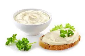 A bowl of dip next to some bread and parsley.